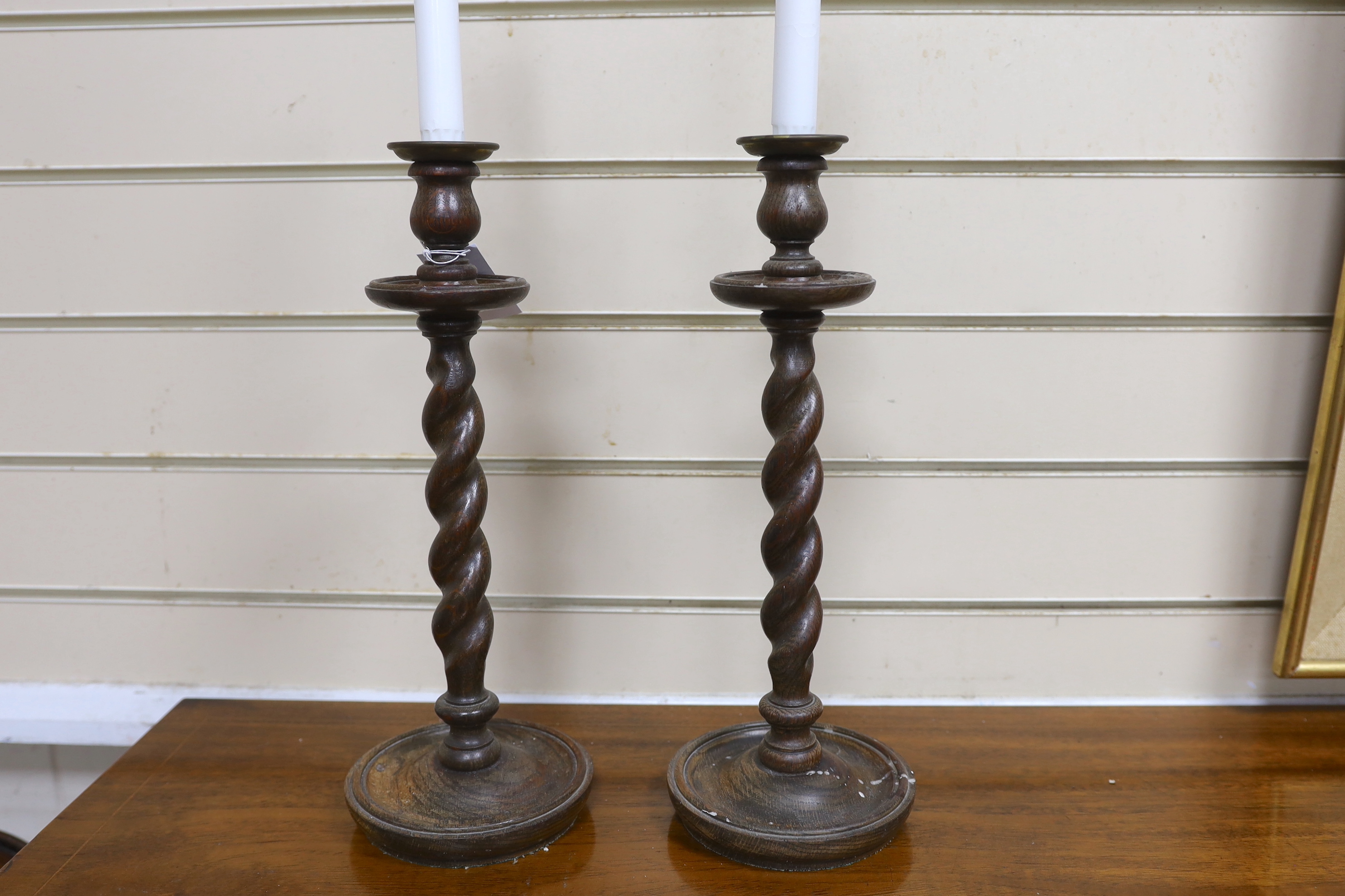 A pair of early 20th century spiral turned candlesticks with brass sconces, height 38cm